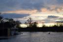 Tom Hunter kayaking over flood water on the cricket pitch at Magdalen College School at sunset