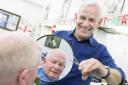 Robert Pewsey, who has been a barber for 50 years, tidies up the hair of his colleague Roger Howard