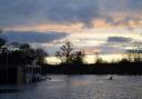 Tom Hunter kayaking over flood water on the cricket pitch at Magdalen College School at sunset