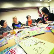 Oxfordshire Reading Campaign volunteers, left to right, Louise Parkinson, Sue Dunne and Dorothy Sym look through children’s books with volunteer manager Bianca Bailey during a training session at the Oxford Central Library. Picture: OX59318