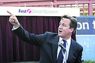 It's on time! David Cameron reacts to an announcement about an approaching train fron the public address system at Charlbury station during his speech on October 14, 2011