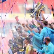 Oxford United's Elliott Moore lifts the trophy on the pitch after the Sky Bet League One play-off final