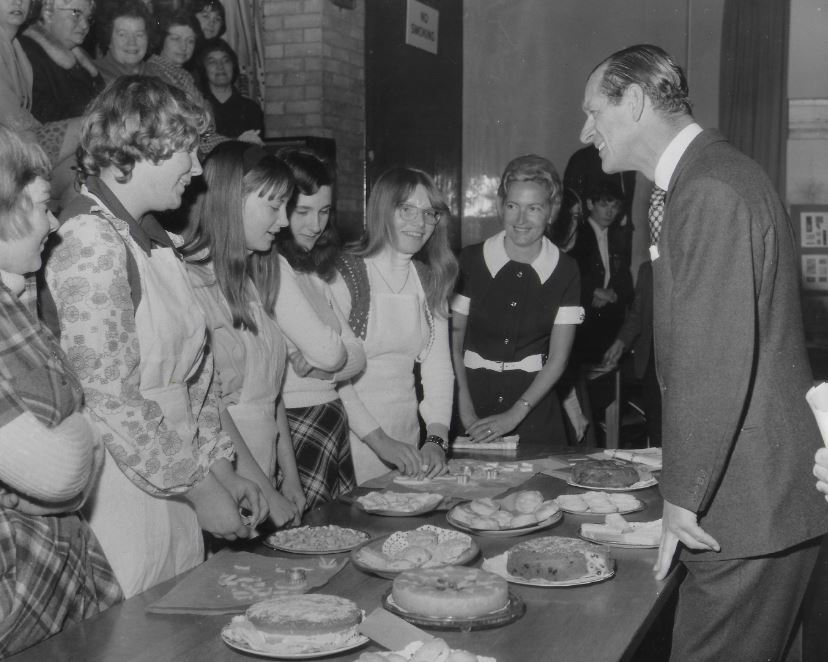 Schoolgirls chat to the Duke as he admires their cakes and pastries during a visit to North Oxfordshire in 1972