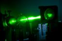 A green laser beam shines through optics at the CLF.