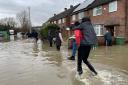 A national picture of people wading through flood water (Callum Parke/PA)