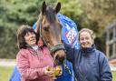 Cheltenham Gold Cup winner Coneygree eats from the trophy as he is led around the yard by owner mother Sara, left, and daughter Lily Bradstock at Old Manor Stables in Letcombe Bassett. Picture: Press Association