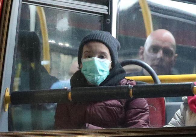 A boy wears a mask on a bus Photo: Yui Mok PA