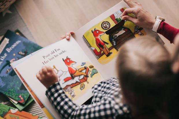 Oxford Mail: A child reading a picture book with their parent. Credit: Canva