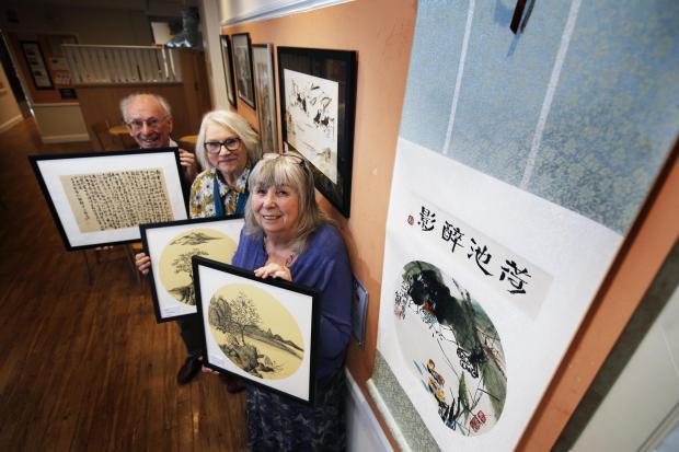 Oxford Mail: They are standing next to a scroll donated by a Chinese artist, Mrs Zhen, 79, who painted the artwork during covid and has donated the scroll to the Group. It will be raffled to raise funds. 