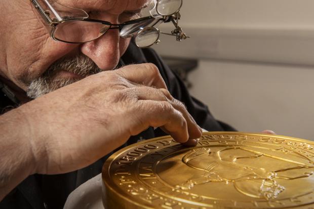 Oxford Mail: Master craftsman Steve Dyer works on the 15 kilo gold coin by hand. Credit: The Royal Mint