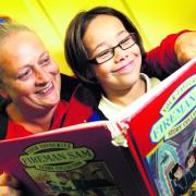 Volunteer Gabi Allen helps Cheyanne Speke at The Blackbird Leys Adventure Playground reading room