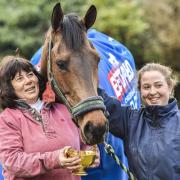 Cheltenham Gold Cup winner Coneygree eats from the trophy as he is led around the yard by owner mother Sara, left, and daughter Lily Bradstock at Old Manor Stables in Letcombe Bassett. Picture: Press Association