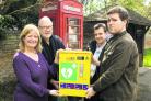 Beth Chesney-Evans and Crispin Evans, left, the parents of Guy, with his twin brother Charles, right, and Tom Bowtell of the parish council, with the defibrillator at the village phonebox