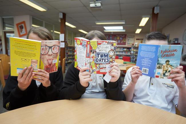 Behind the books are Larkmead School pupils Priti Gurung, Sophie Truby and Harry Wheatley