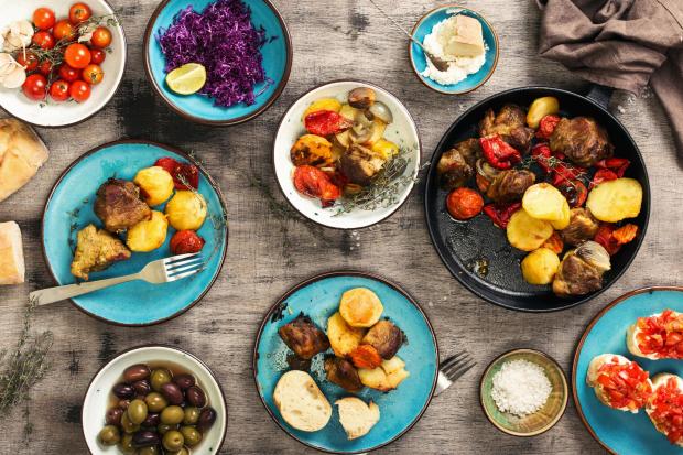 Food table, fried meat with vegetables in a pan, salad and appetizers, top view Picture Getty